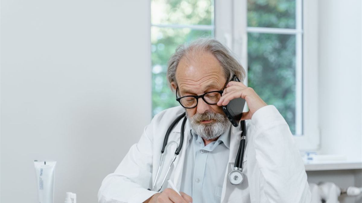 Médecin âgé au téléphone à son bureau