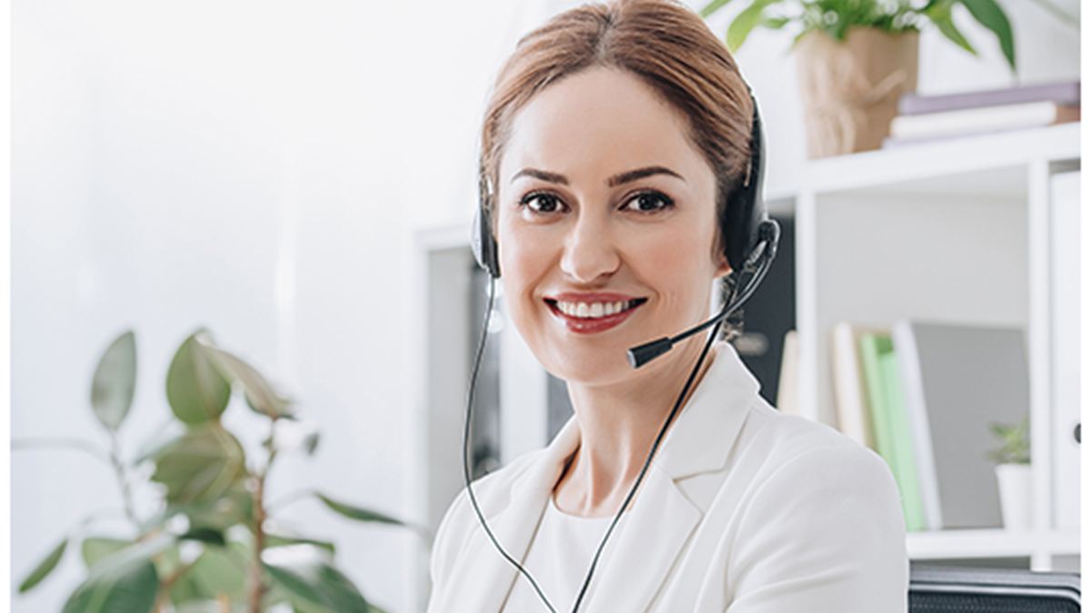 Secrétaire souriante avec casque à son bureau